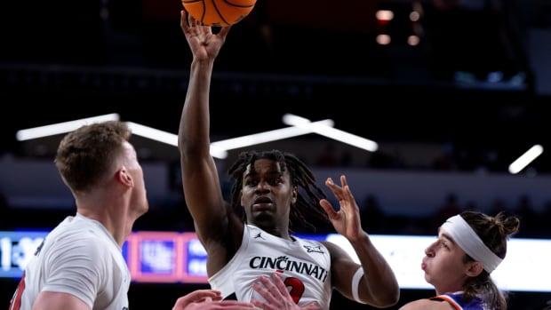 Cincinnati Bearcats guard Jizzle James (2) passes the ball to Cincinnati Bearcats forward Viktor Lakhin (30) as Evansville Purple Aces guard Gage Bobe (0) guards him in the first half of the NCAA basketball game between Cincinnati Bearcats and Evansville Purple Aces at Fifth Third Arena in Cincinnati on Friday, Dec. 29, 2023.